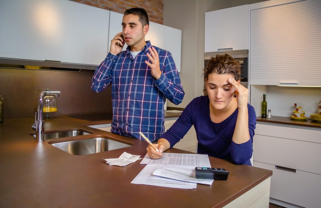 Angry man arguing at phone while woman calculating credit lines