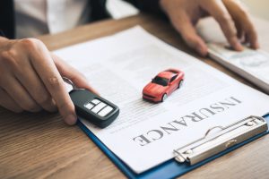 Car salespeople are holding car keys by submitting to new car buyers with car insurance concept.