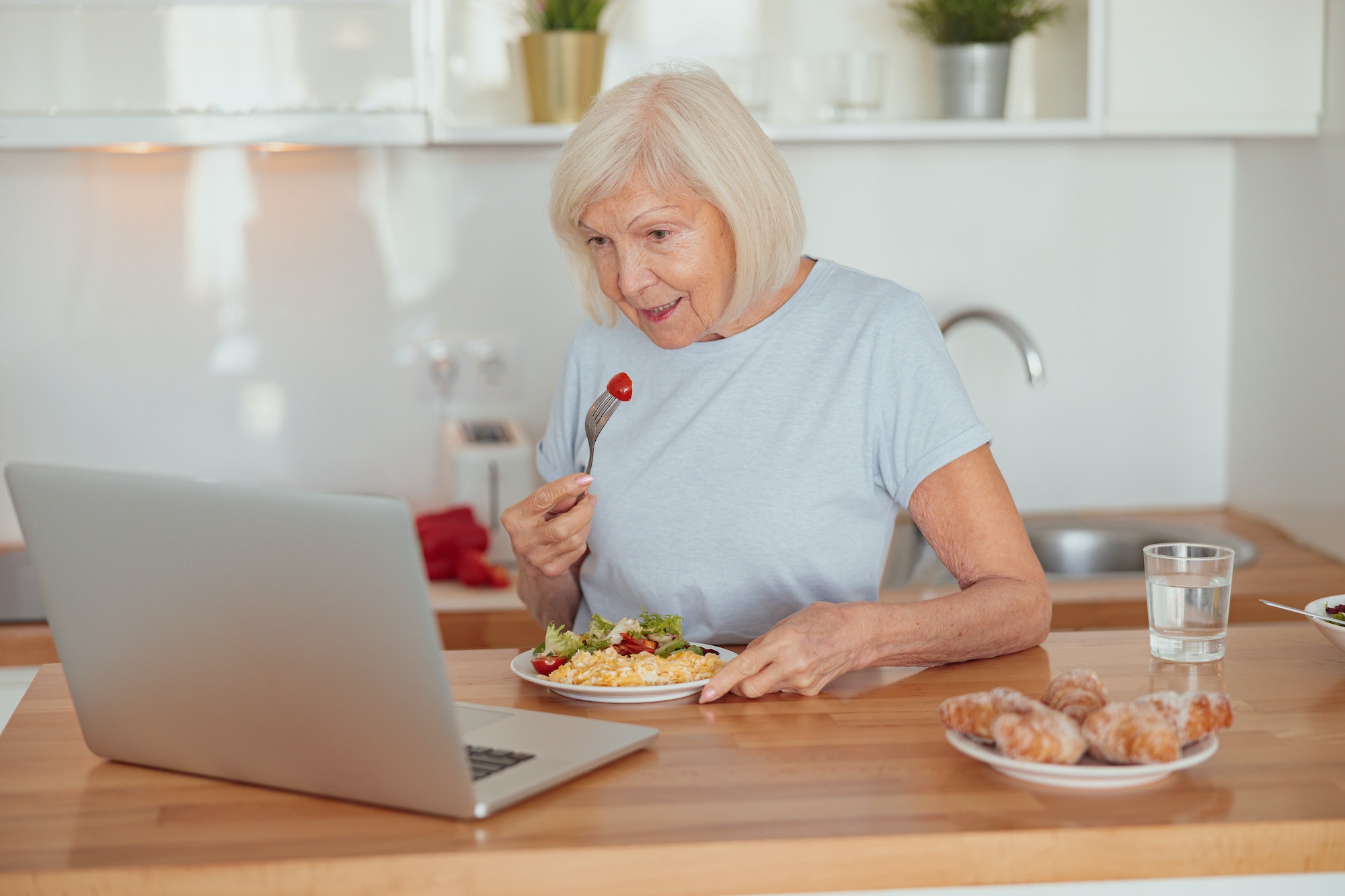 Concentrated senior woman eating breakfast at home