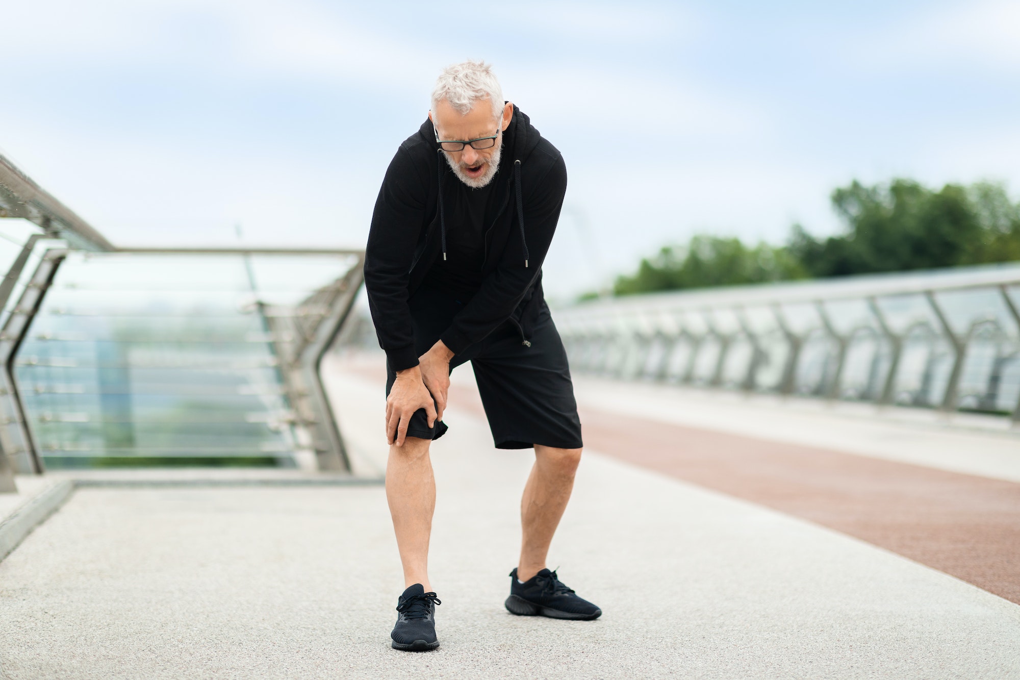 Senior man suffering with knee pain during workout outdoor